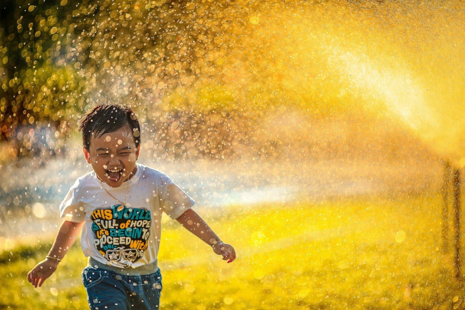 A young child happily playing in water at golden hour