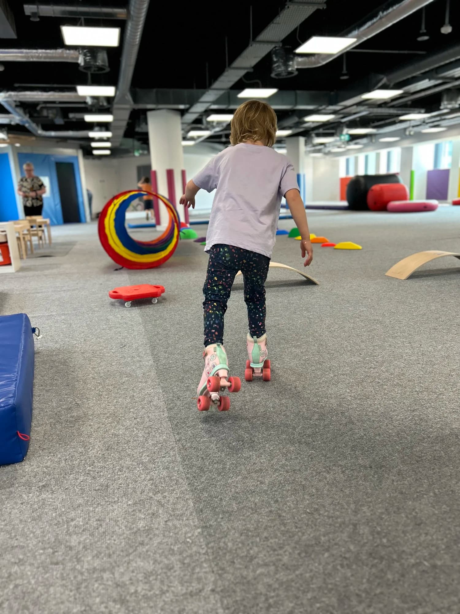 A young girl rollerskating through an indoor play area