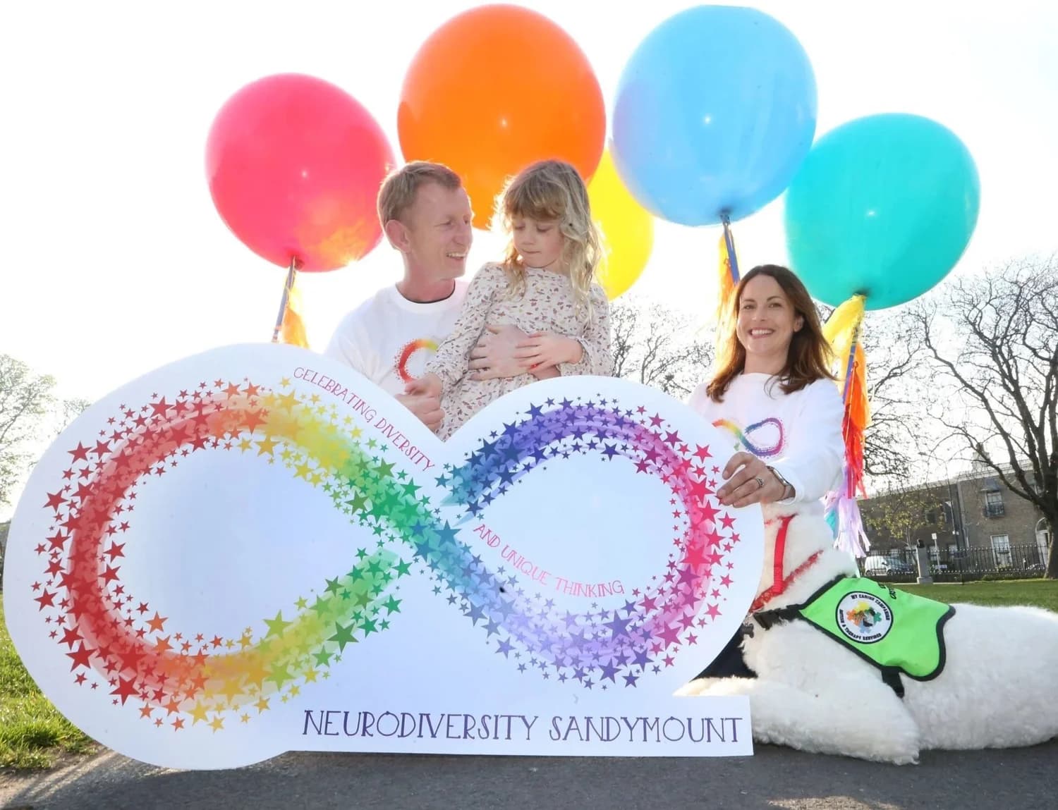 People holding a rainbow infinity sign celebrating diversity and unique thinking, outdoors