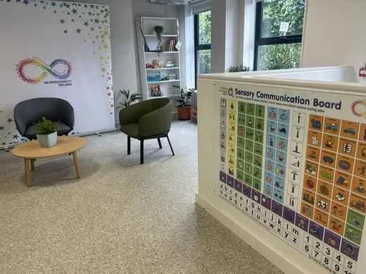 A calm seating area at the NDI centre with armchairs and a large sensory communication board
